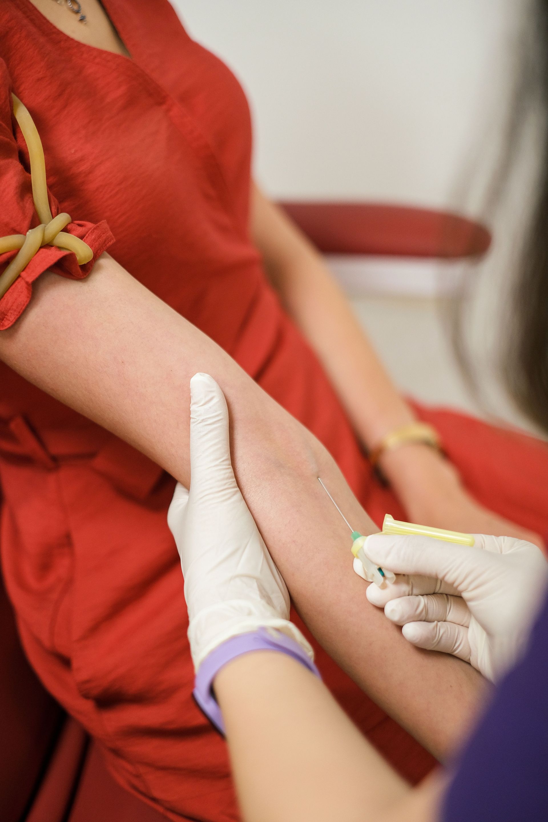 Close-up of a healthcare professional drawing blood from a patient's arm with gloves.