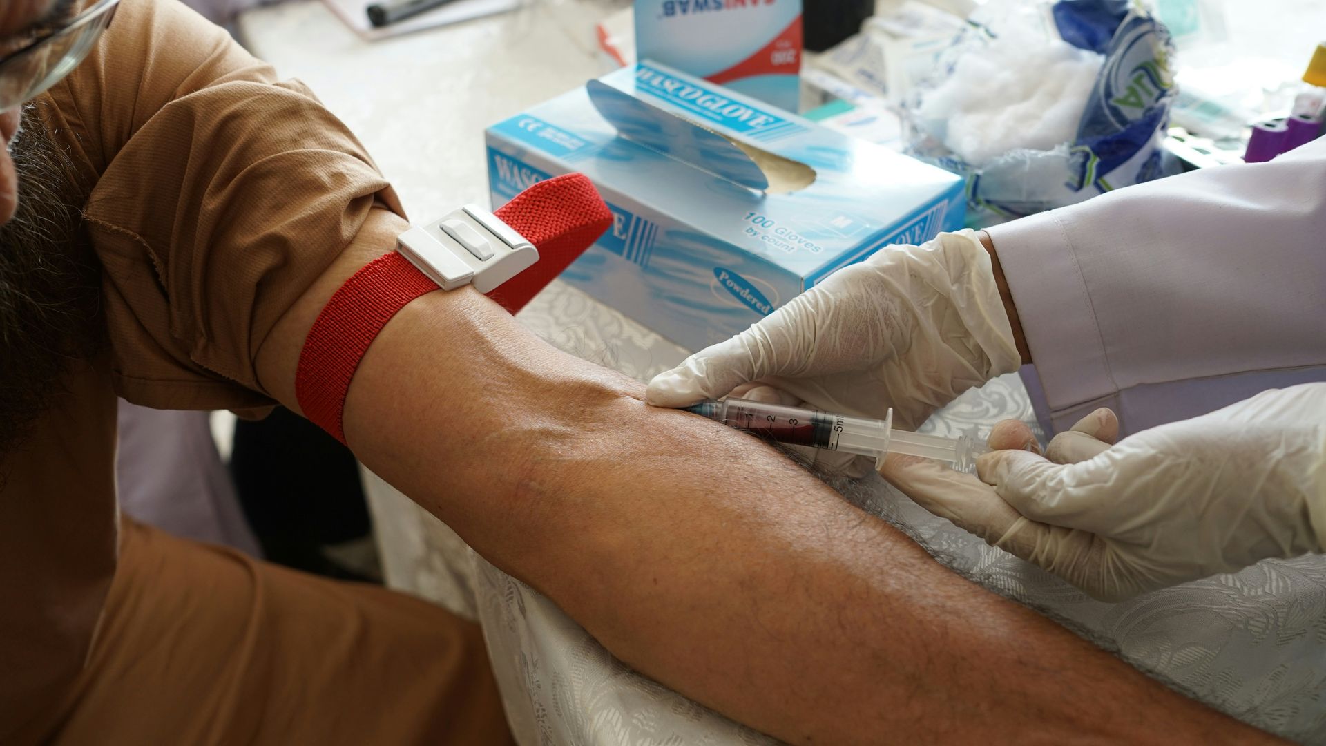 Medical professional drawing blood from a patient's arm.