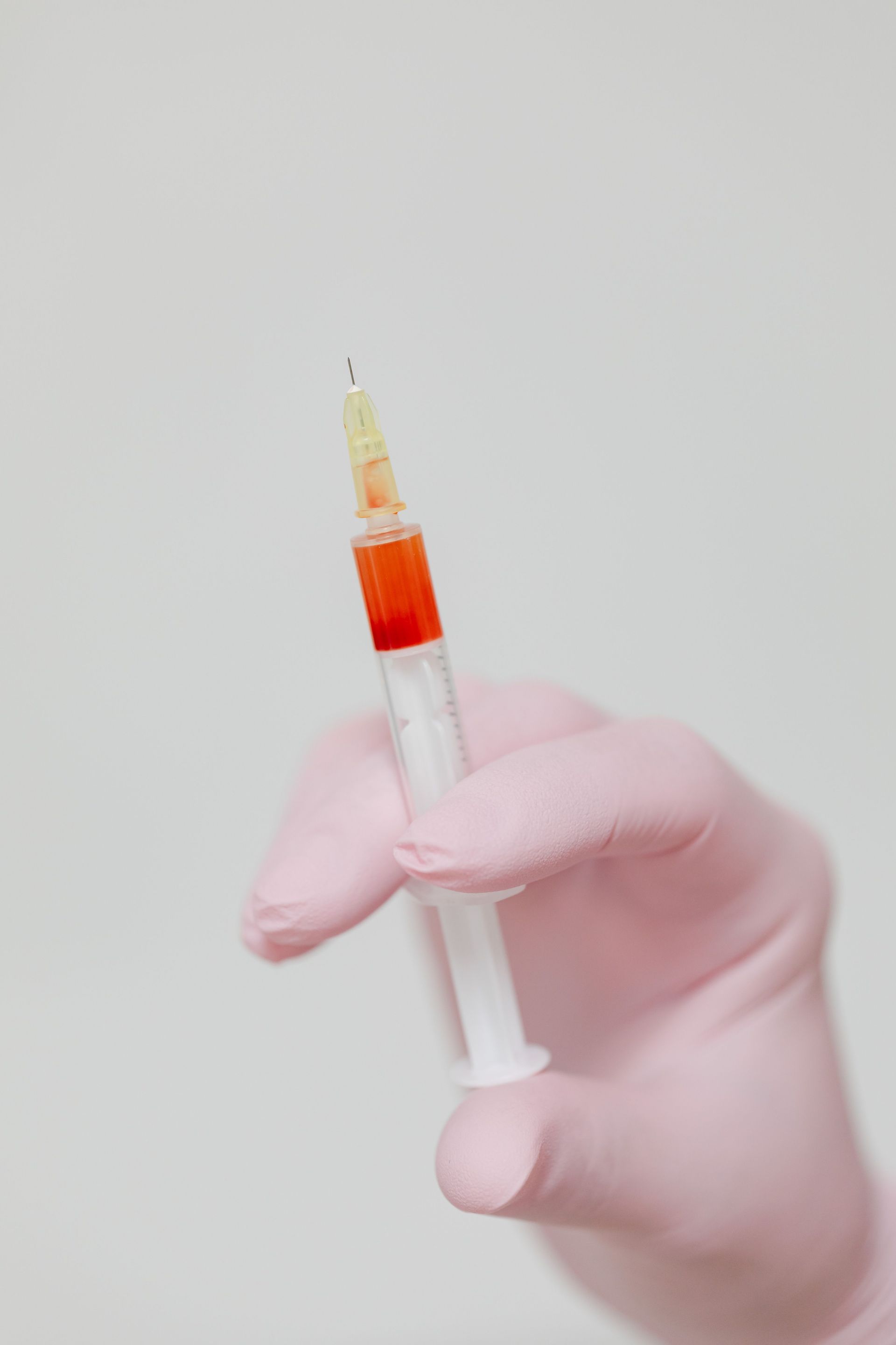 Close-up image of a gloved hand holding a syringe containing blood. Ideal for medical themes.