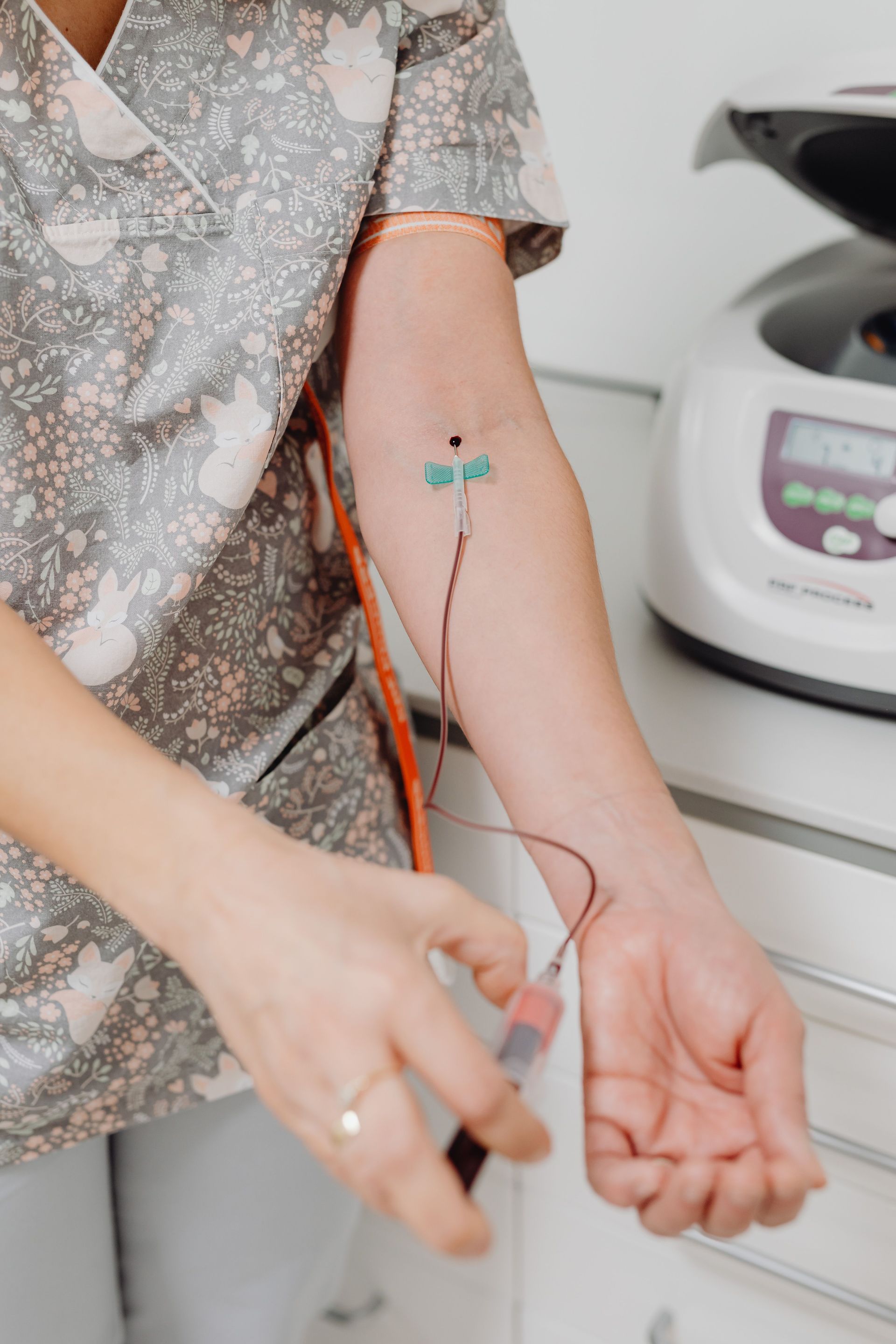 Close-up of a nurse drawing blood from a patient's arm in a medical setting.